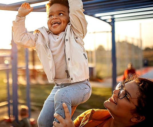 Mom helping son do monkey bars.