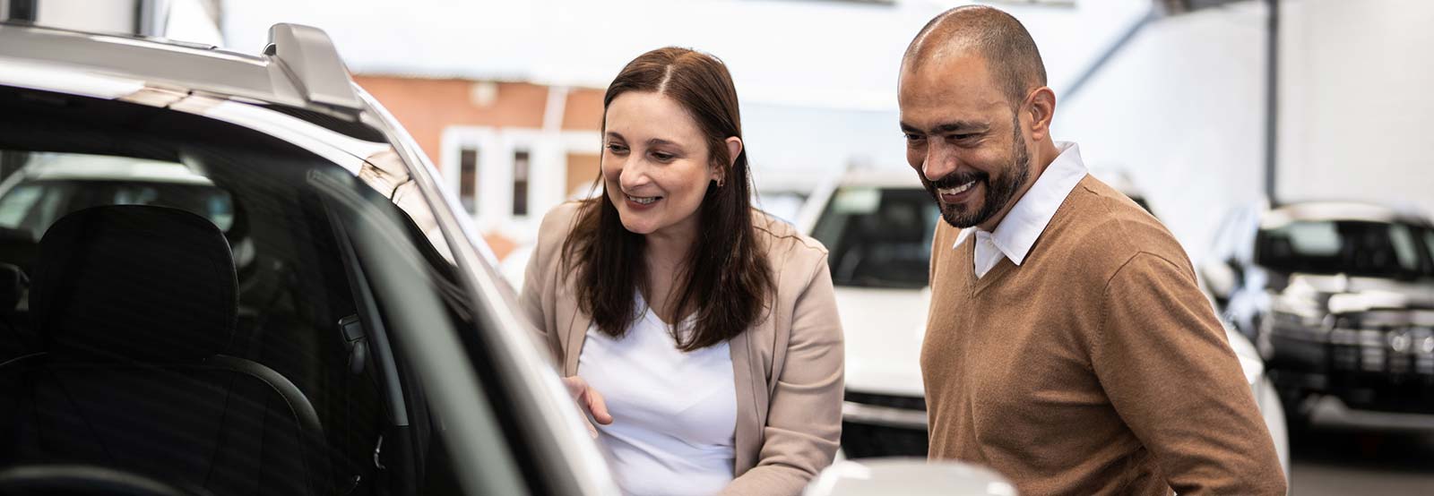 Couple looking at new car on lot.