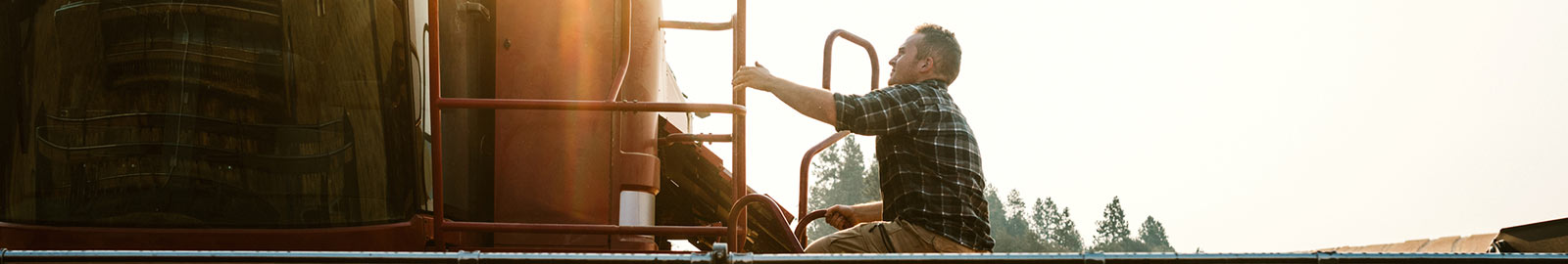 Man climbing onto farm equipment.